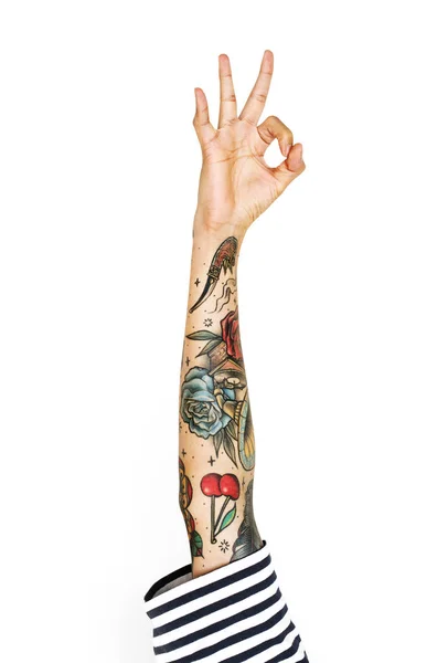 human hand with tattoos gesturing ok sign with fingers