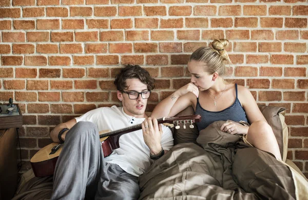 白人夫妇在床上 男子弹吉他 — 图库照片