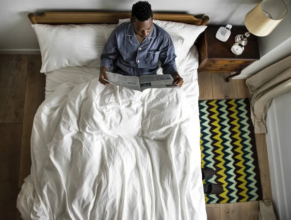 African Man Bed Reading Newspaper — Stock Photo, Image