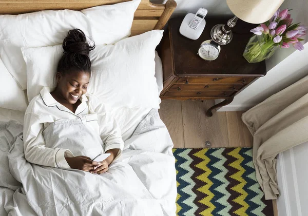 Усміхаючись Африканською Жінкою Використання Мобільного Телефону Ліжку — стокове фото