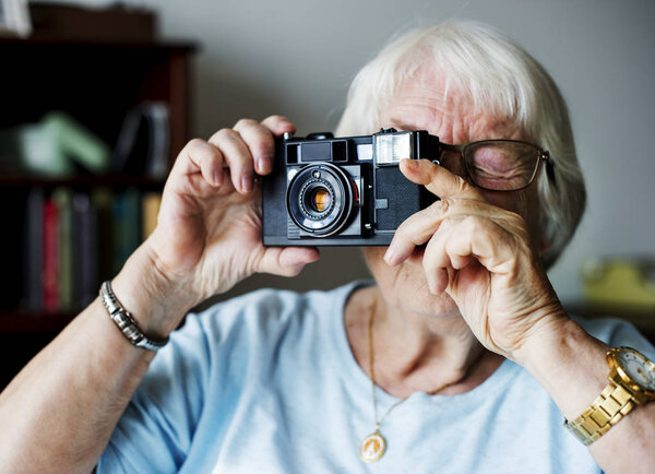 Senior woman taking a photo at retro photo camera