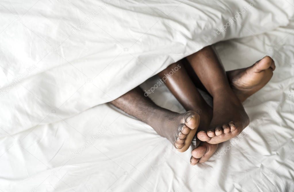 Black couple sleep together, legs under the blanket