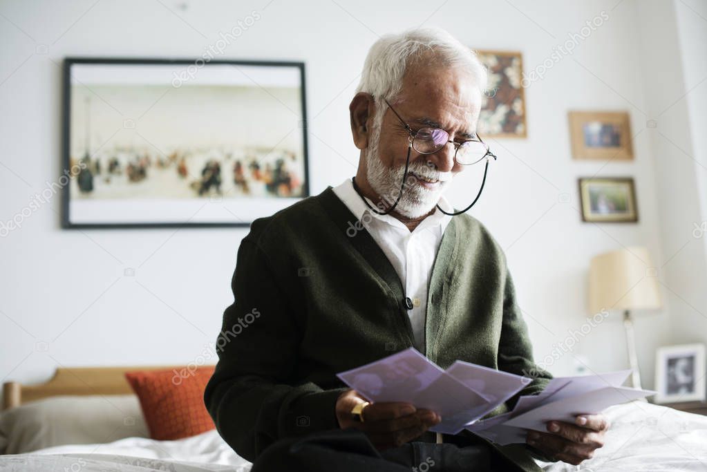 elderly Indian man at nursing home looking to photos 