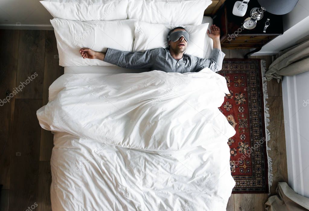 Man on bed sleeping with sleeping mask 
