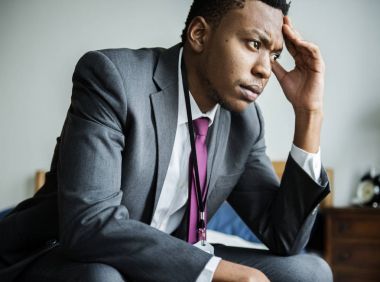 Yatağın üstüne oturan takım elbiseyle ilgili Afrika adam 