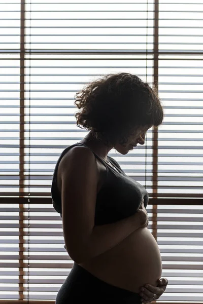 Gravid Kvinne Som Står Ved Vinduet – stockfoto