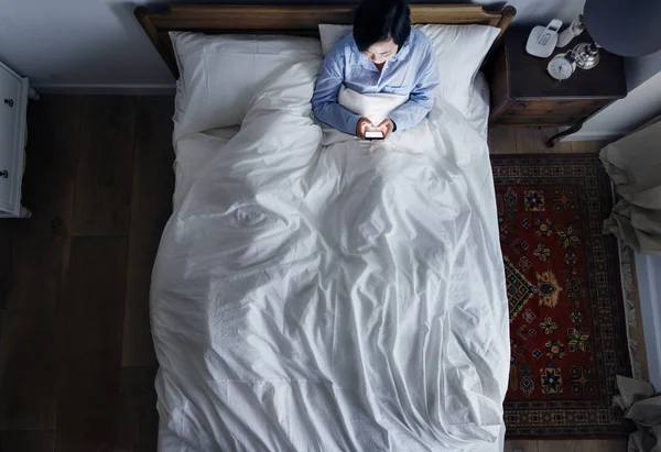 女人在床上使用手机在黑暗中 — 图库照片