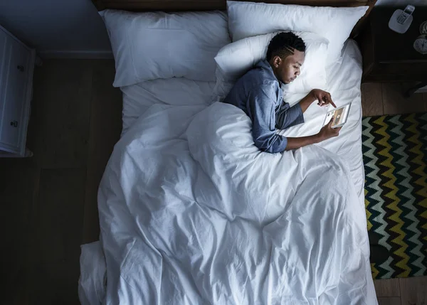 Άνθρωπος Στο Κρεβάτι Μια Ψηφιακή Συσκευή Στο Σκοτάδι — Φωτογραφία Αρχείου