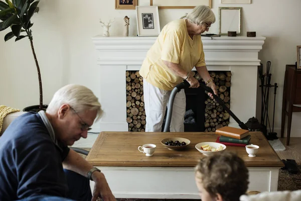 爷爷和孙子坐在沙发上 奶奶把地板清空到起居室 — 图库照片