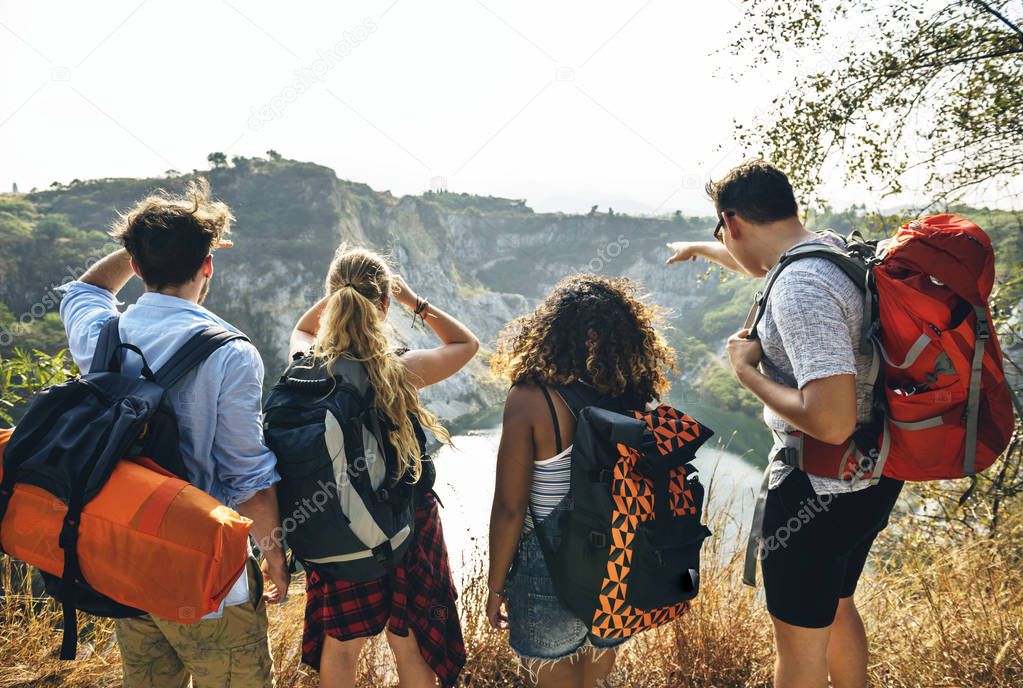 Back view on friends with Backpacks looking to mountains and lake  