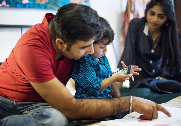 Indian Family Reading Book Looking Mobile Phone — Stock Photo, Image