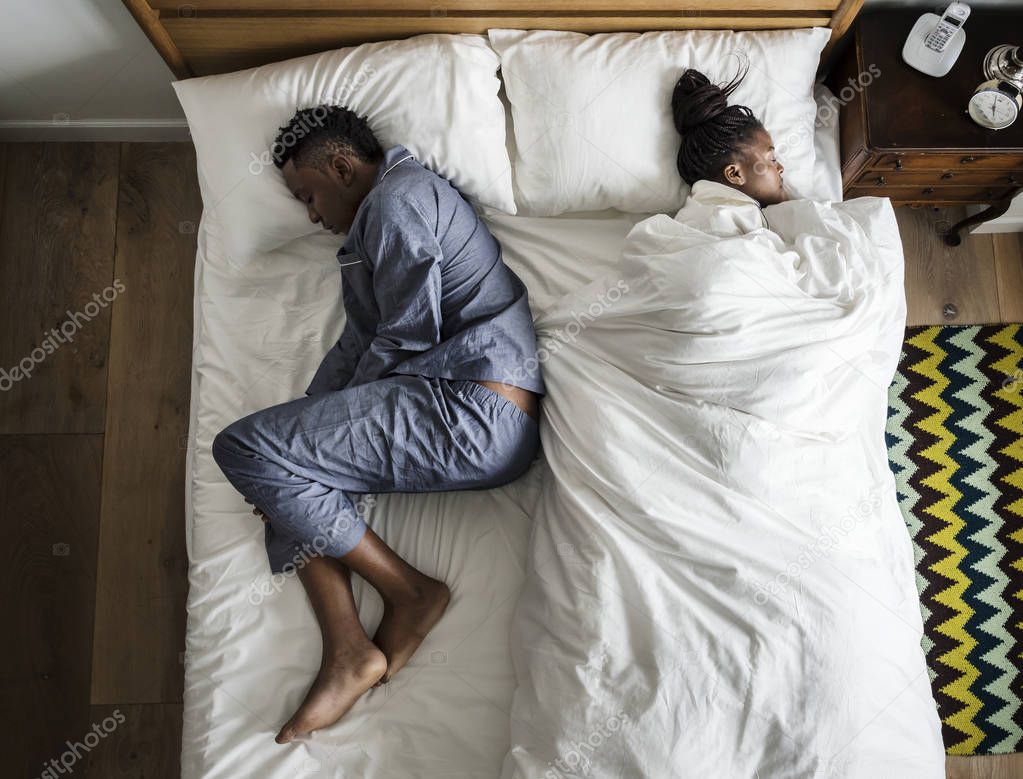 African couple sleeping back to back, woman took all blanket 