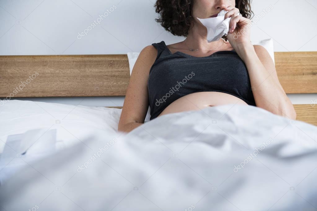 Sick pregnant woman on bed