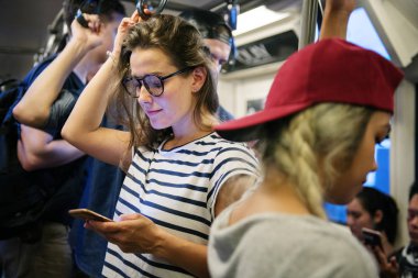 Metroda bir akıllı telefon kullanan genç kadın