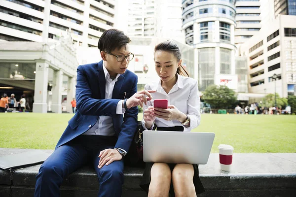 Asiatische Geschäftsleute Sitzen Auf Brüstung Und Nutzen Gemeinsam Mobiltelefon — Stockfoto