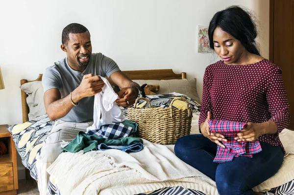 アフリカのカップルの寝室で一緒に服を折りたたみ — ストック写真