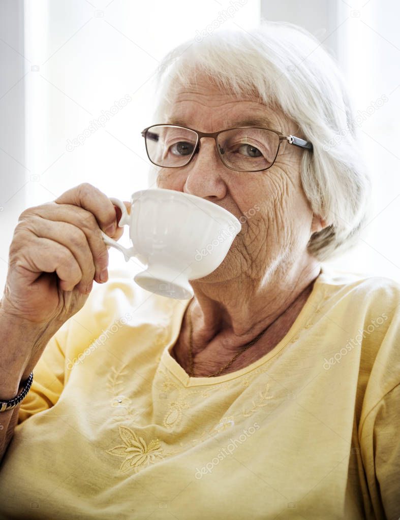 Senior woman drinking tea while looking at the camera