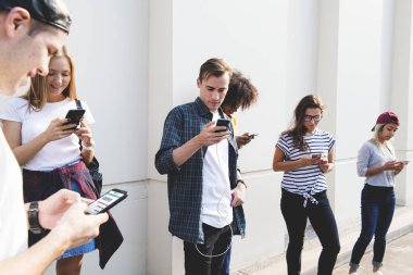 Arkadaşlar açık havada birlikte akıllı telefonlar kullanan ve soğutma