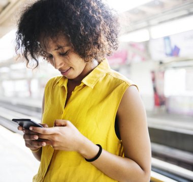 Metro istasyonunda bir akıllı telefon kullanan genç kadın