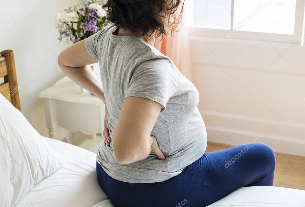 Pregnant woman with back pain on bed
