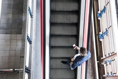 Yürüyen merdiven bir akıllı telefon kullanan adam
