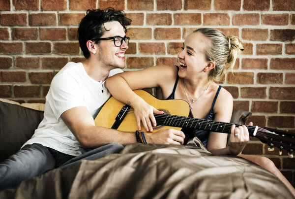 Caucasian couple playing guitar together