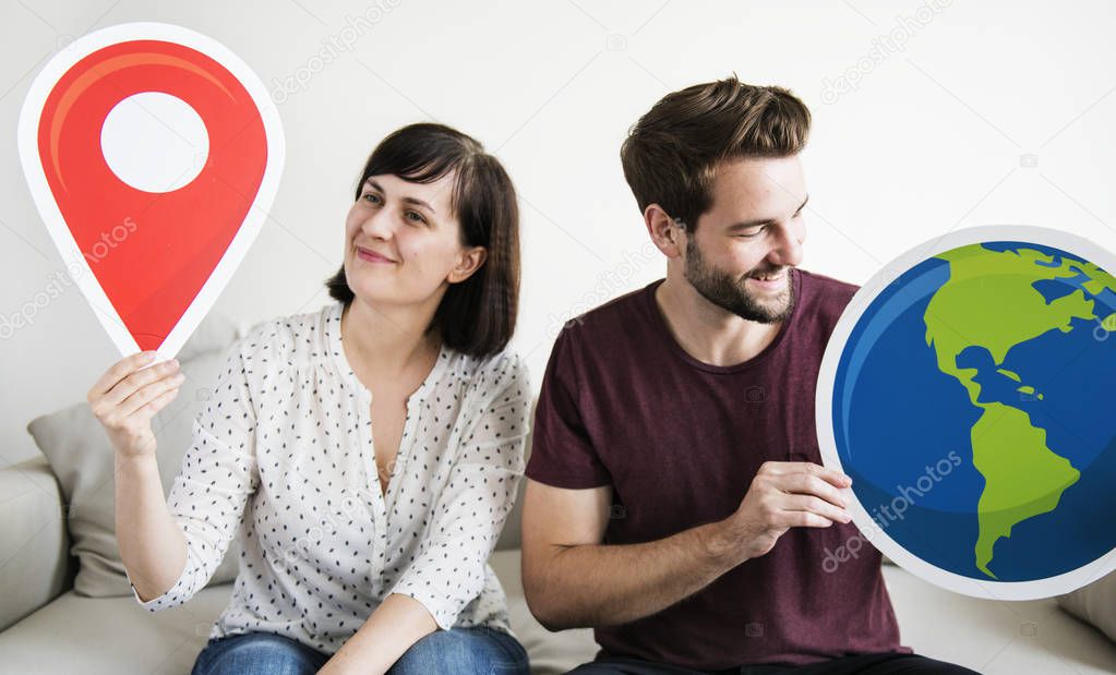 A wanderlust couple holding globe and location icon