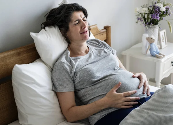 Pregnant woman with labor pain in bed