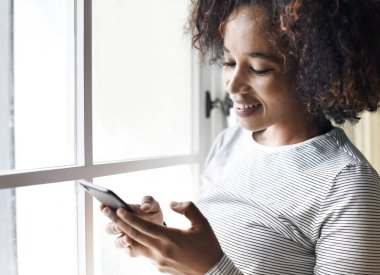 Akıllı telefon kullanan gülümseyen bir kadın.
