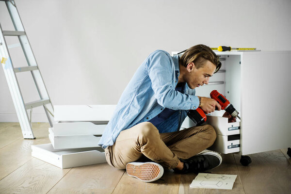 Man using electronic drill install cabinet