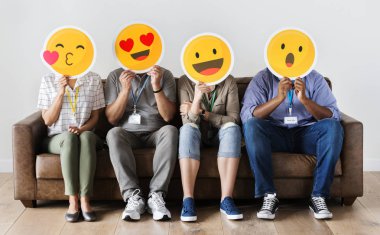 Oturma ve emojis kurulları ile karşı karşıya kapsayan çeşitli insanlar