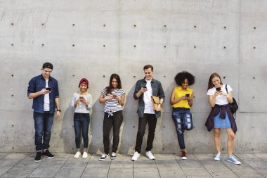 Grup genç arkadaşlar açık havada birlikte akıllı telefonlar kullanan ve soğutma