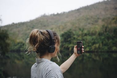 Akıllı telefon ve kulaklık ile müzik dinlemek doğada yalnız kadın