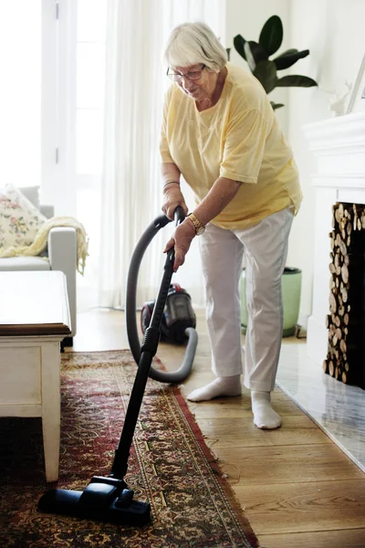 Seniorin Saugt Teppich — Stockfoto