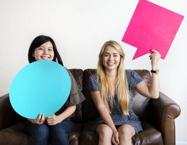 Konuşma balonları kopya alanı için tutan mutlu Asya ve beyaz kadın 