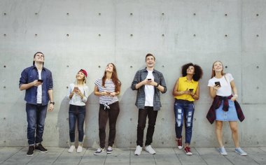 Grup genç arkadaşlar açık havada bakmak smartphones kullanarak