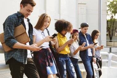 arkadaşlar açık havada akıllı telefonlar kullanarak
