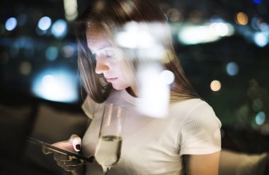 Bir akıllı telefon Çatıdaki bar akşamları kullanan ciddi genç kadın