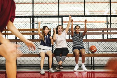 Genç kızlar basketbol oynarken çocuklar tezahürat