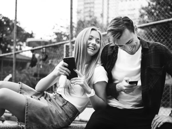 快乐可爱的年轻夫妇在公园使用智能手机在一起 黑白相间 — 图库照片
