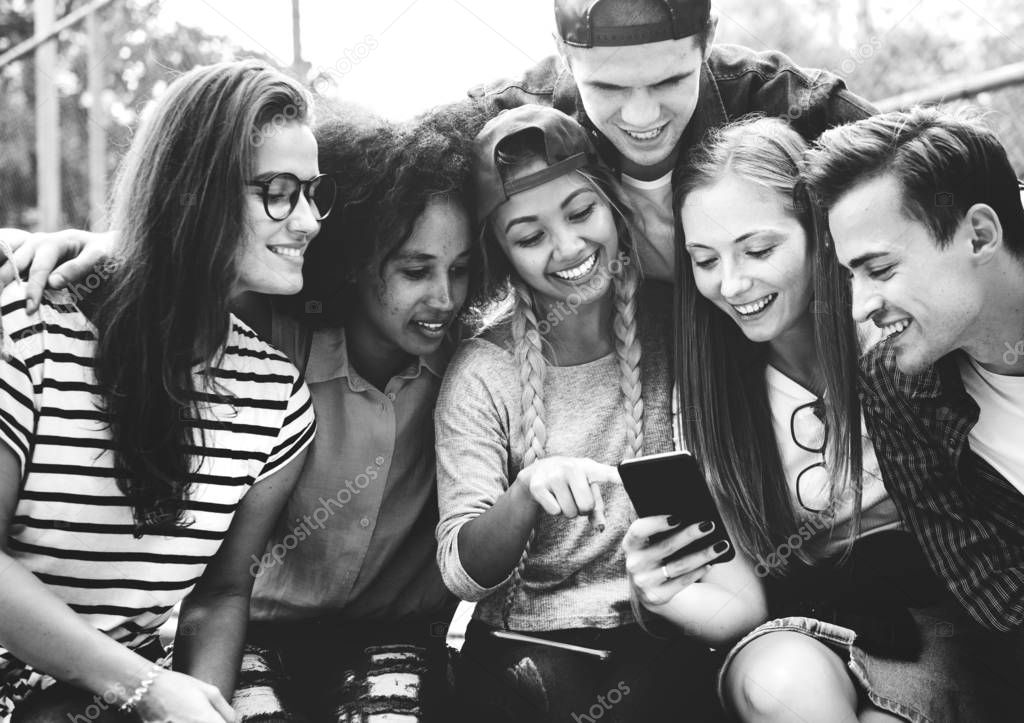 Friends in the park looking using smartphone, millennial and youth culture concept, black and white