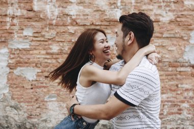 Bir tuğla duvar tarafından güzel Asyalı Çift