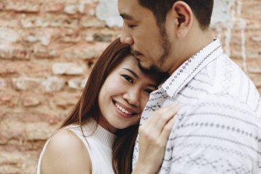 Bir tuğla duvar tarafından güzel Asyalı Çift