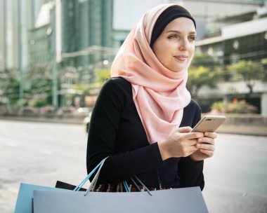 Çanta alışveriş ve cep telefonu tutan islam kadın 