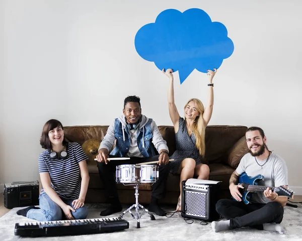 musical band having rehearsal in room with drums, guitar and keyboard, woman holding blue speech cloud