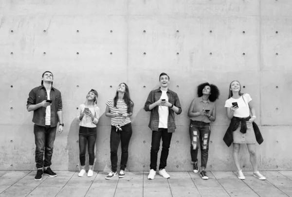 Grupa Młodych Ludzi Zewnątrz Pomocą Smartfonów Patrząc Górę Czarno Białe — Zdjęcie stockowe