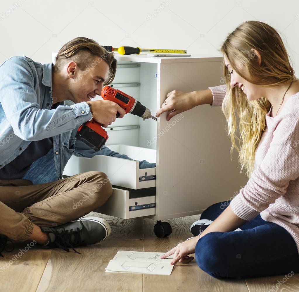 Man using electronic drill with woman 