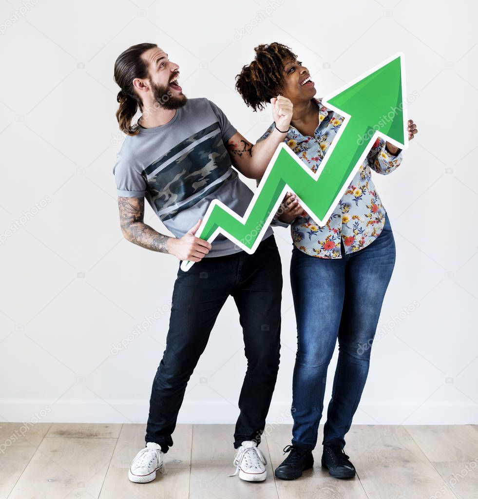 Happy smiling interracial couple holding a growth arrow growth and success concept