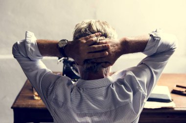 Kafasında düşünceli oturan çapraz kolları olan beyaz adam arkadan görünüş