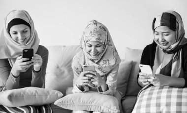 Kanepede oturan ve akıllı telefonlar kullanarak islam kadın grubu 